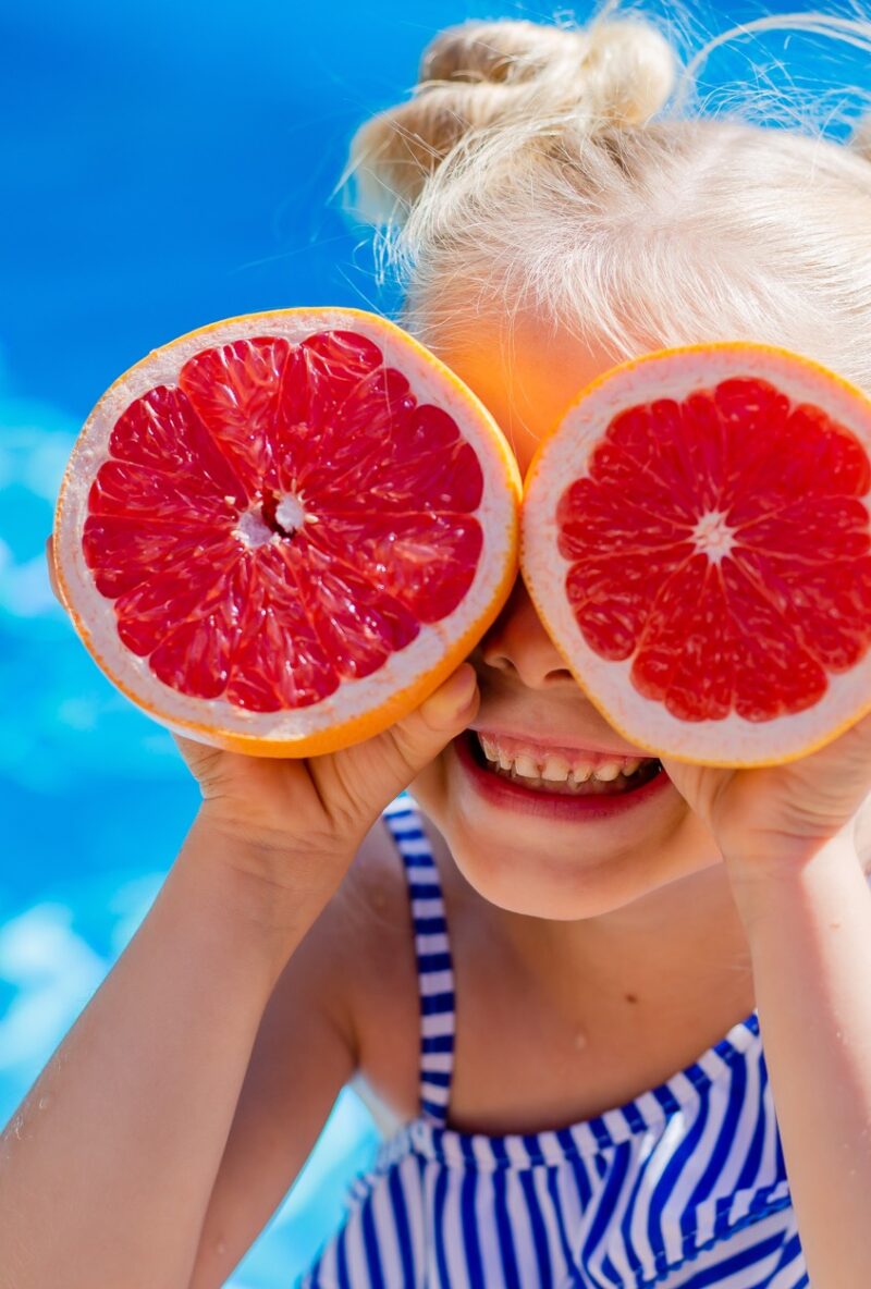 Playful Girl with Fruit Glasses: Joyful Moment of Fruit-Stacking Fun